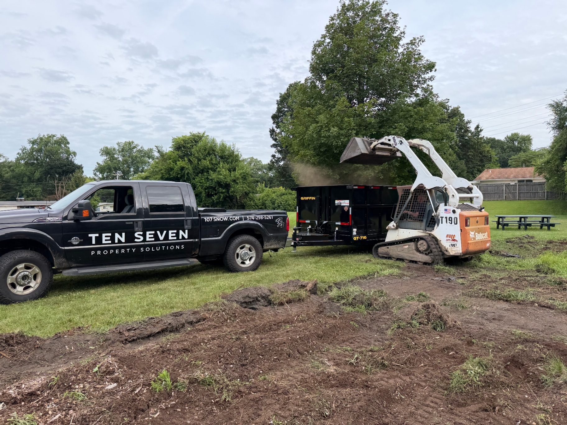 Ten Seven Property Solutions truck, dump trailer, and skid steer on a land clearing job